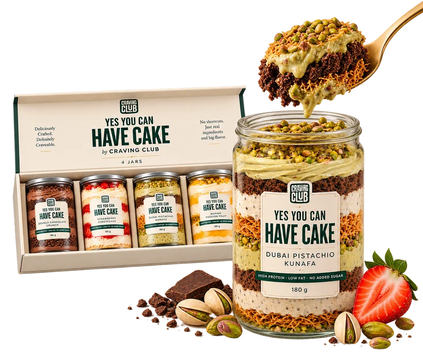 Open Craving Club box of four jars beside a Dubai Pistachio Kunafa jar with a spoonful of cake, chocolate, pistachios and strawberry